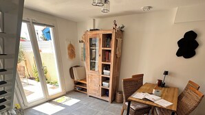 Een woonkamer met een bank, een eettafel met stoelen, een houten kast en een groot raam.
