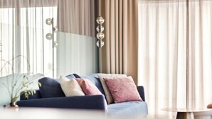 Un salon moderne avec un canapé bleu foncé, de nombreux coussins, un grand lampadaire et une table ronde.