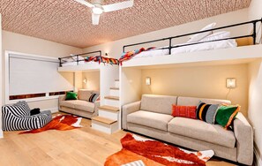 A modern interior with a bunk bed, a sofa, a striped bean bag, and a staircase. - Chic Nash Home, 4bd/4ba w/ Hot Tub & Rooftop! (Nashville)