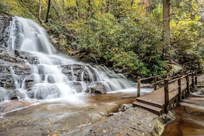 Ein Wasserfall stürzt über Felsen, mit einer Holzbrücke.