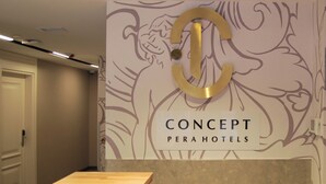 Een receptiebalie met een blauw patroon, een muur met een groot 'C'-logo en de tekst 'CONCEPT Pera Hotels'.