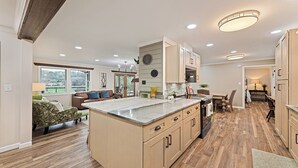 A spacious kitchen with a large island, wooden cabinets, and a dining area with a table and chairs.