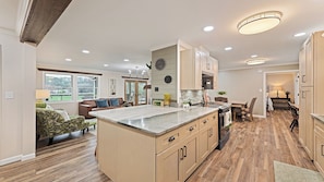 A spacious kitchen with a large island, wooden cabinets, and a dining area with a table and chairs.