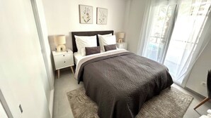 Un dormitorio con una cama grande, dos mesitas de noche y una ventana con cortinas.