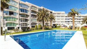 Un hotel con piscina, varios balcones y palmeras.