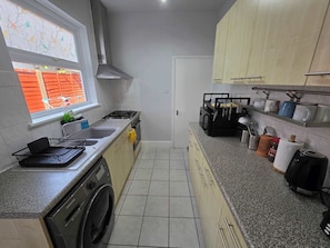 A kitchen with a washing machine, a stove, and a sink.
