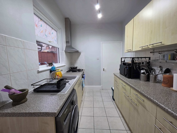 A compact kitchen with a washing machine, a stove, and a microwave.