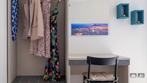 Una camera moderna con scrivania integrata, una sedia, un armadio e un dipinto con vista sulla città.