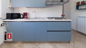 Una cucina moderna con mobili blu, un fornello a gas, un forno a microonde e una macchina da caffè.
