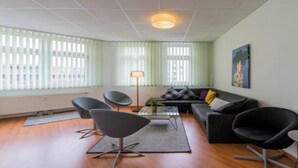 A modern living room with a sofa, two armchairs, a coffee table, and a floor lamp.