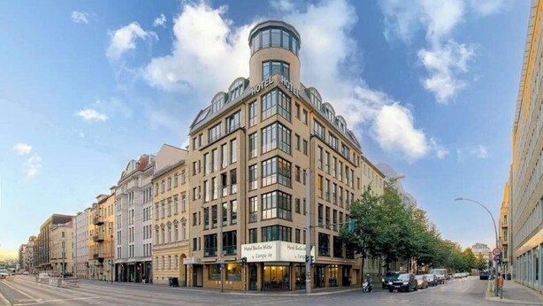 A corner building with multiple floors, a prominent rounded corner, and signs for 'Hotel Berlin Mitte' and 'Hotel Berlin Mitte'.