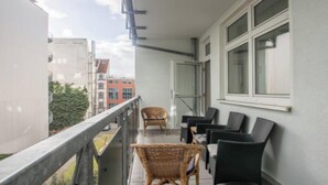 A balcony with wicker chairs and a view of buildings.