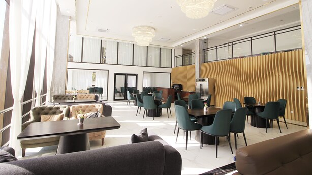 A modern hotel lobby with a seating area, a reception desk, and a large window. - CARREY HOTEL- Accommodation BB-MICE (Lusaka)