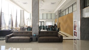 A spacious lobby with a high ceiling, a large column, and a seating area with sofas. - CARREY HOTEL- Accommodation BB-MICE (Lusaka)