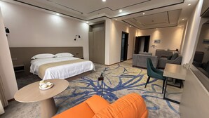 A hotel room with a bed, a sofa, a small table, and a desk. - CARREY HOTEL- Accommodation BB-MICE (Lusaka)