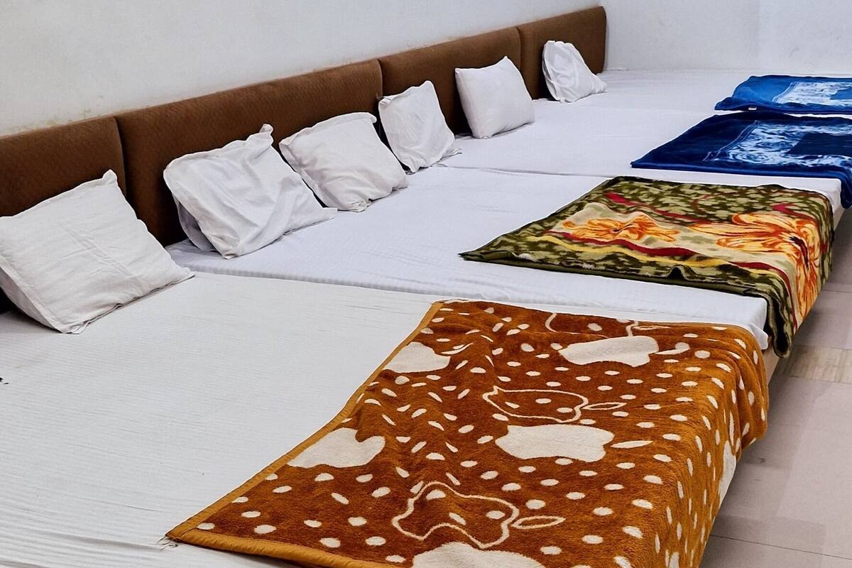 A hotel room with a long bed, multiple pillows, and a patterned blanket.