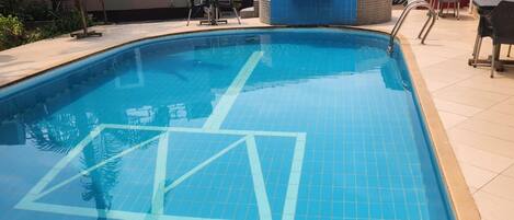 A swimming pool with tiled flooring and a clear blue water surface.