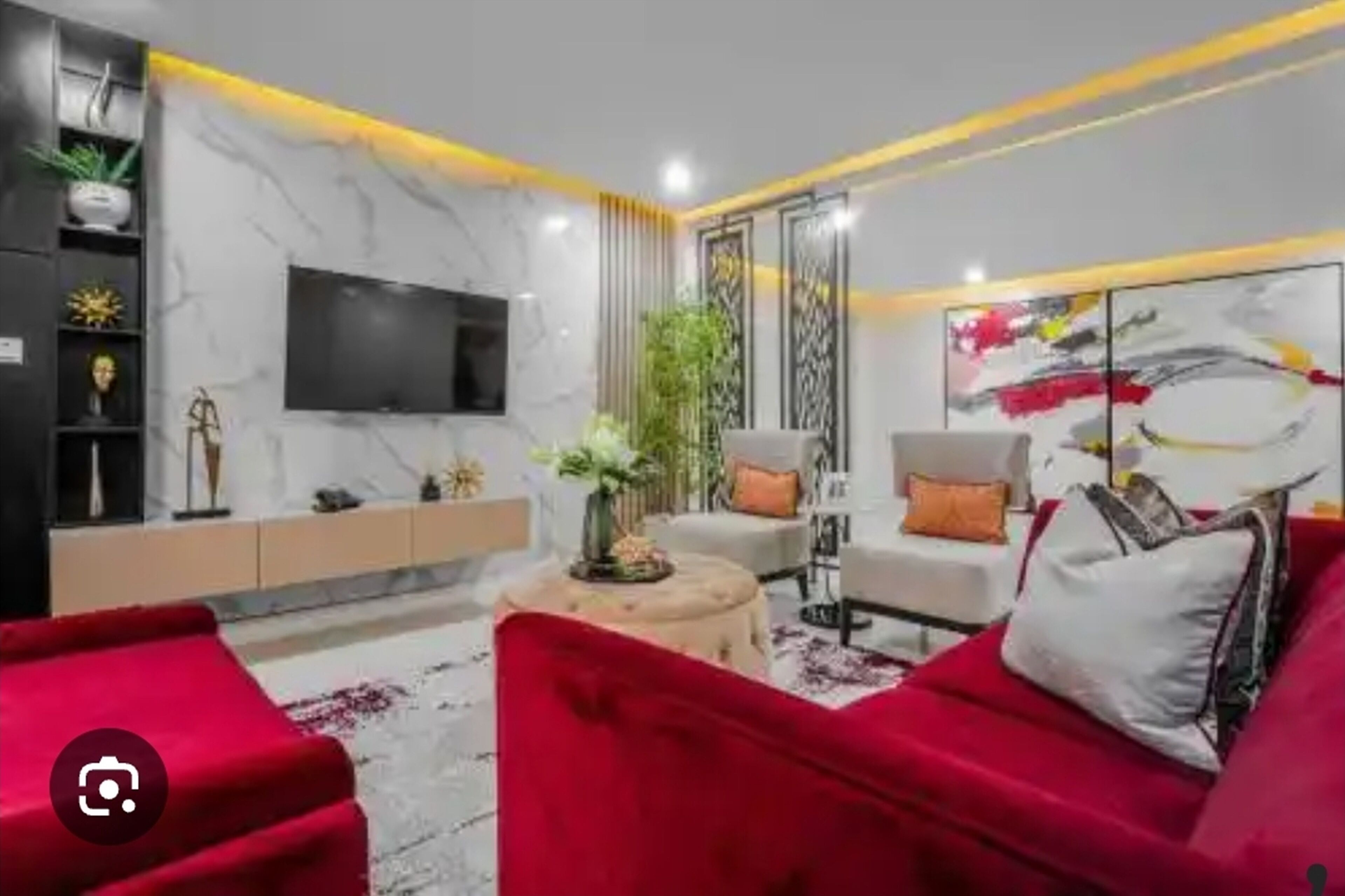 Un salon moderne avec un canapé rouge, un téléviseur fixé au mur et une plante décorative.