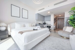 Une chambre d’hôtel moderne équipée d’un grand lit, d’un bureau, d’une chaise et d’un petit canapé.