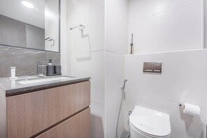 Une salle de bain moderne avec un plan de toilette en marbre, un lavabo, des toilettes et une douche.