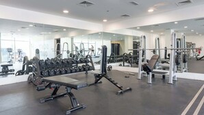 A modern gym with various weightlifting equipment, mirrors, and a clean, spacious layout. - StayShort - Stylish Modern Studio in Living Garden 2 (JVC)