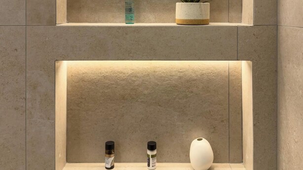 Two wall-mounted shelves with lighting, each holding a small plant, a bottle, and a container. - Mixalakopoulou Luxury Apartment (Athens)