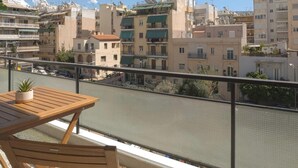 A balcony with a view of a cityscape, a wooden table, and a potted plant. - Mixalakopoulou Luxury Apartment (Athens)