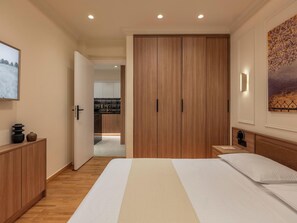 A modern bedroom with a large bed, wooden wardrobe, and a view into the kitchen. - Mixalakopoulou Luxury Apartment (Athens)