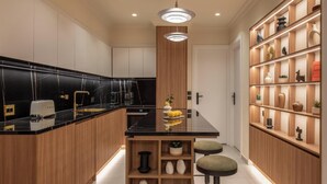 A modern kitchen with wooden cabinetry, black countertops, and a central island with stools. - Mixalakopoulou Luxury Apartment (Athens)