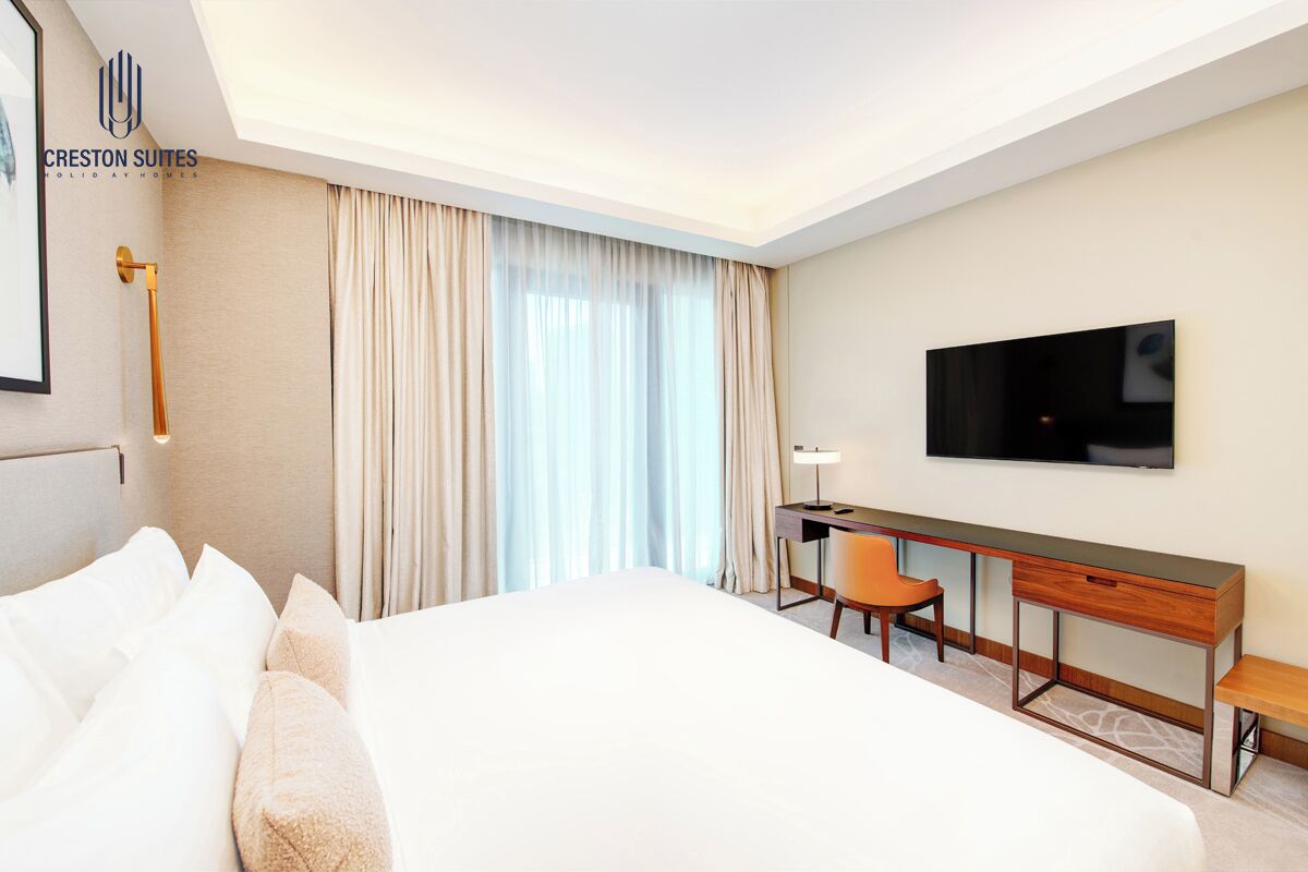 Een hotelkamer met een groot bed, een bureau, een stoel, een televisie en een raam met gordijnen.