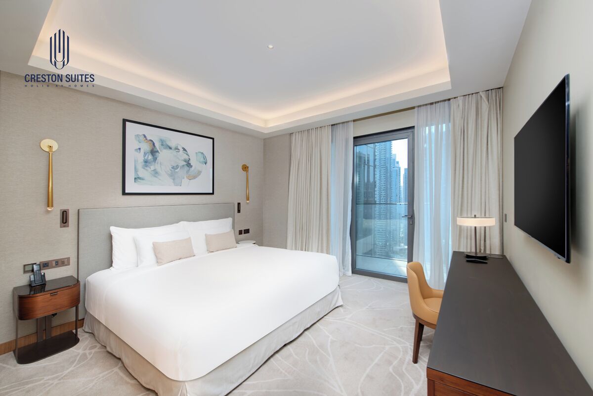 Habitación de hotel con una cama grande, un escritorio, un televisor y vistas a la ciudad.