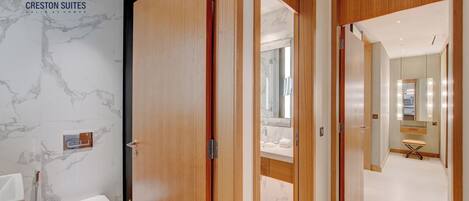 Et badeværelse på et hotel med en marmorvæg, en trædør og en hvid vask.