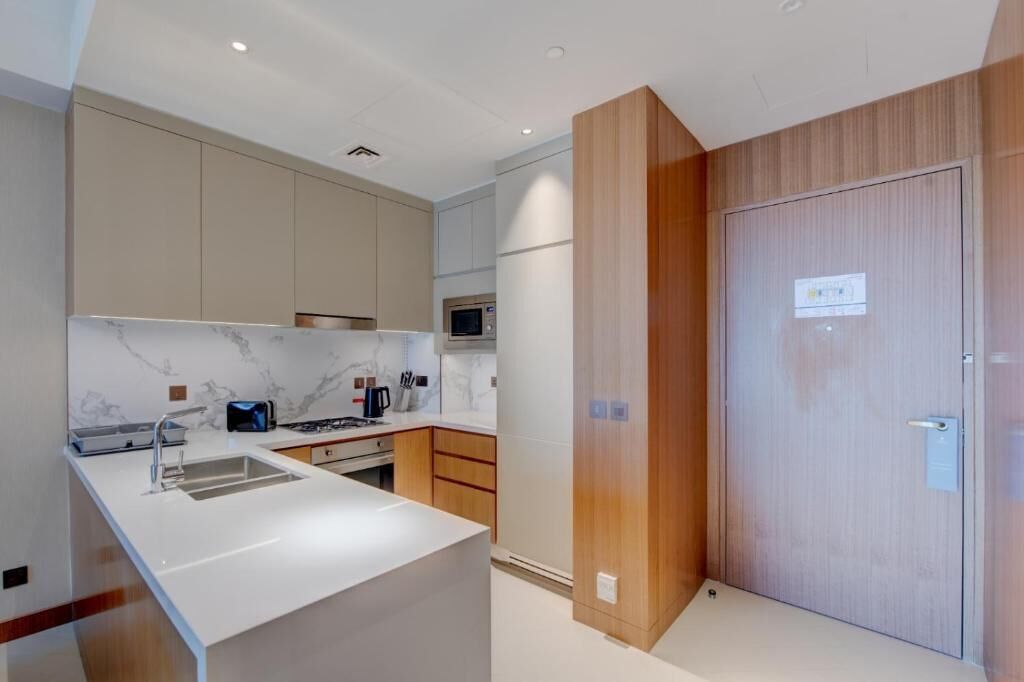 Una cocina moderna con encimera de mármol, armarios empotrados y una puerta de madera.