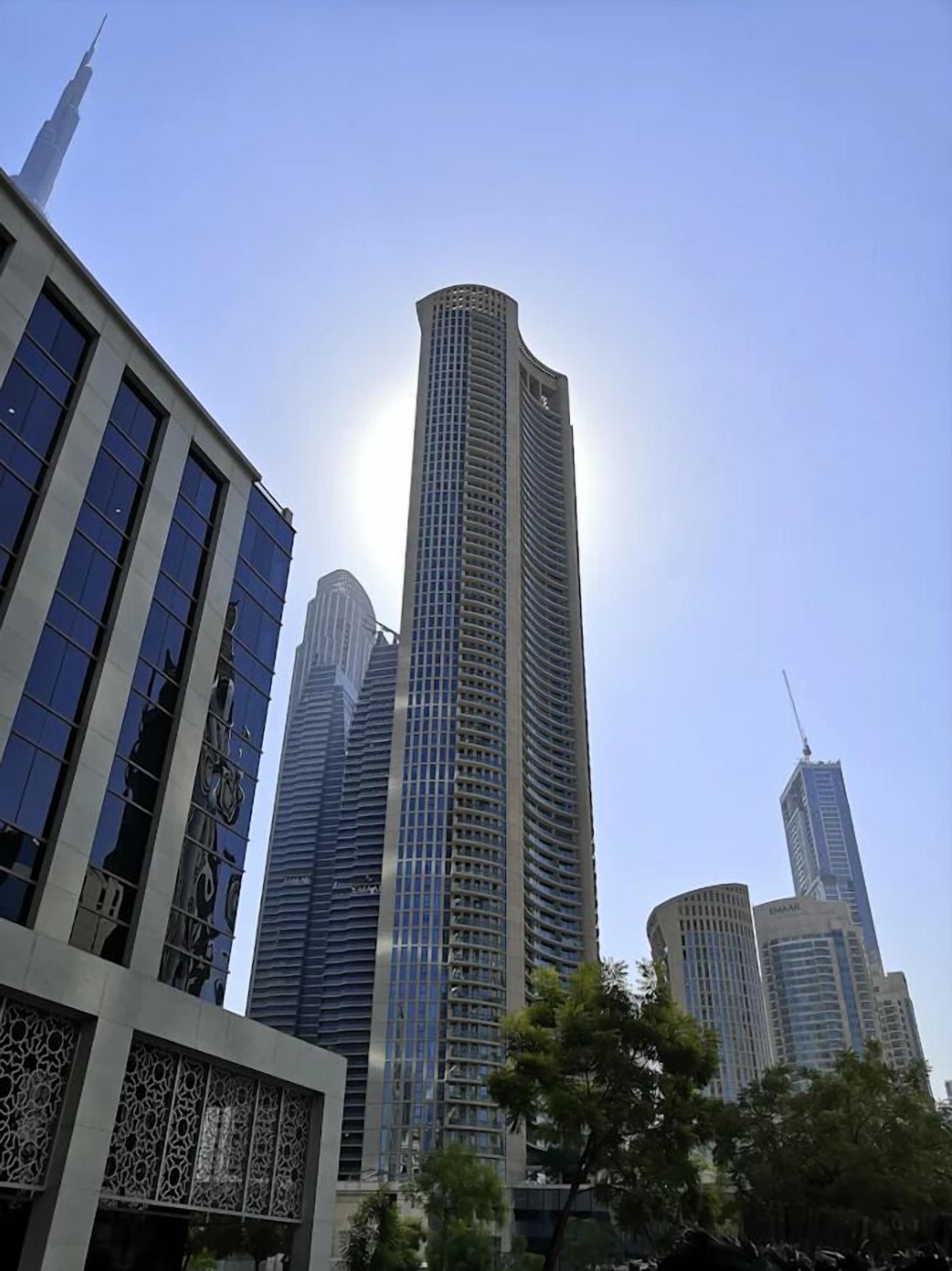 A high-rise building with a modern design, featuring a prominent central tower and surrounding structures.