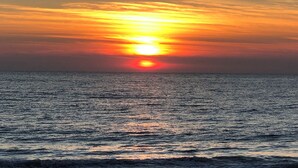 Ein Sonnenuntergang über dem Meer, ruhige Wasseroberfläche spiegelt den Himmel.