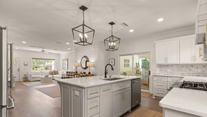 A modern kitchen with white cabinetry, a central island, and pendant lighting.