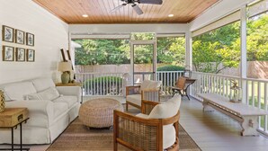 A covered porch with a ceiling fan, wicker furniture, a white sofa, and a bench.