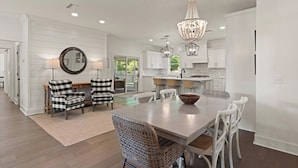 A spacious kitchen with white cabinetry, a large island, and a chandelier.