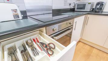 A kitchen with a microwave, toaster, and a drawer with utensils.