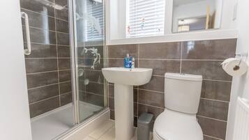 A bathroom with a glass shower enclosure, a pedestal sink, and a toilet.