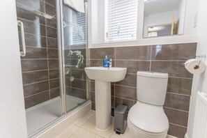 A bathroom with a glass shower enclosure, a pedestal sink, and a toilet.