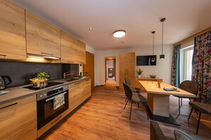 Una cocina moderna con armarios de madera, horno empotrado y comedor con mesa y sillas de madera.
