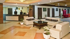 A hotel lobby with a reception desk, sofas, a coffee table, and a chandelier. - Hotel CK International By Pax Hotels (Shimla)