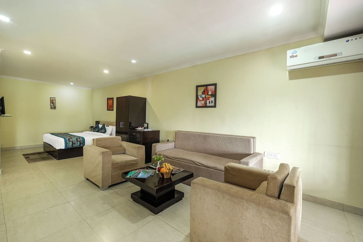 Una habitación de hotel con una cama, un sofá, una mesita de centro y un televisor.