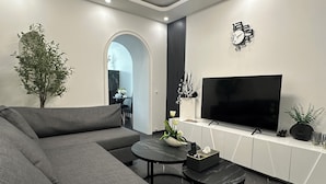 Un soggiorno moderno con un ampio divano componibile, una televisione a schermo piatto e un arredamento minimalista.