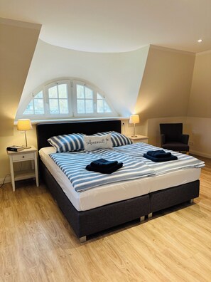 Relax in this serene bedroom with a large bed, bedside tables, and a comfortable chair.