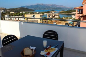 A balcony with a table set for breakfast, overlooking a coastal town and a body of water. - Hotel Artur2 (Ksamil)