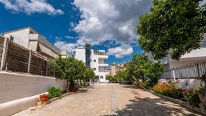 Un patio de hotel con un sendero de piedra, rodeado de edificios blancos y árboles.