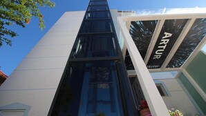 Un edificio moderno con fachada de vidrio y un letrero que dice 'ARTUR HOTEL'.