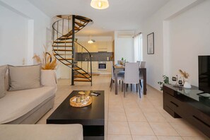 Stunning living space with a spiral staircase, beige sofa, and dining area.